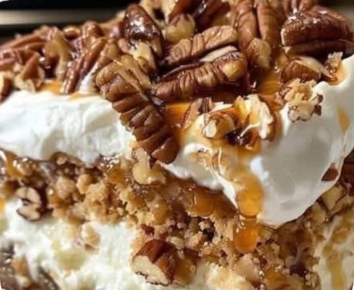 A close-up shot of a slice of Old-Fashioned Bread Pudding with Vanilla Sauce. The bread pudding has layers of bread, nuts, and a creamy filling, topped with whipped cream, pecans, and caramel sauce.